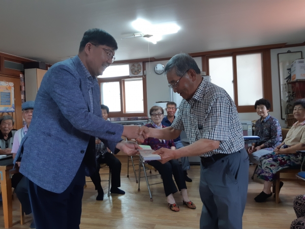 김동윤 면장(왼쪽)이 둔포3리 정창용 노인회장에게 이미용권을 전달하고 있다. (사진제공 : 아산시청)